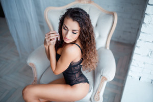 Perfect, sexy body of young woman wearing seductive lacy black lingerie. Beautiful female in bodysuit on luxury vintage chair portrait